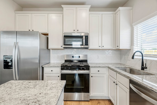 kitchen featuring white cabinets, sink, light stone countertops, and stainless steel appliances