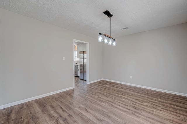 spare room with light hardwood / wood-style flooring and a textured ceiling