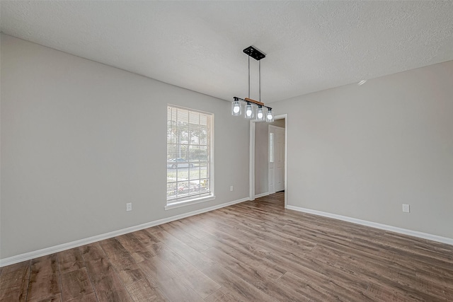 unfurnished dining area with wood-type flooring and a textured ceiling