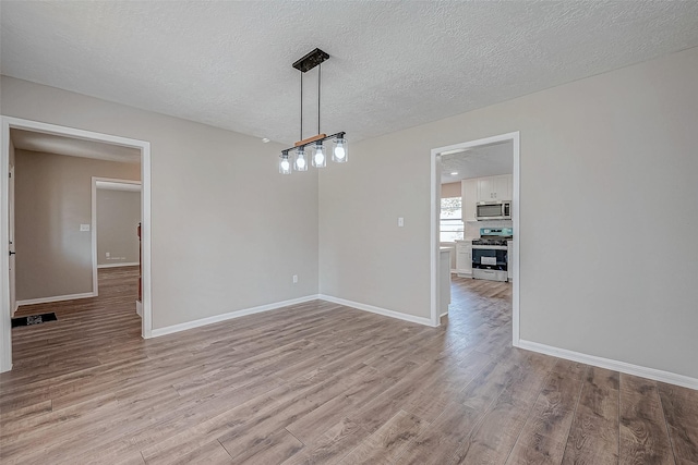 unfurnished dining area with a textured ceiling and light hardwood / wood-style flooring