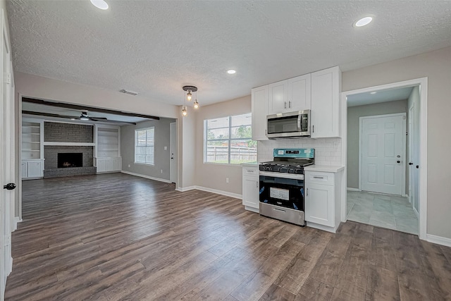 kitchen featuring white cabinetry, a fireplace, a textured ceiling, and appliances with stainless steel finishes