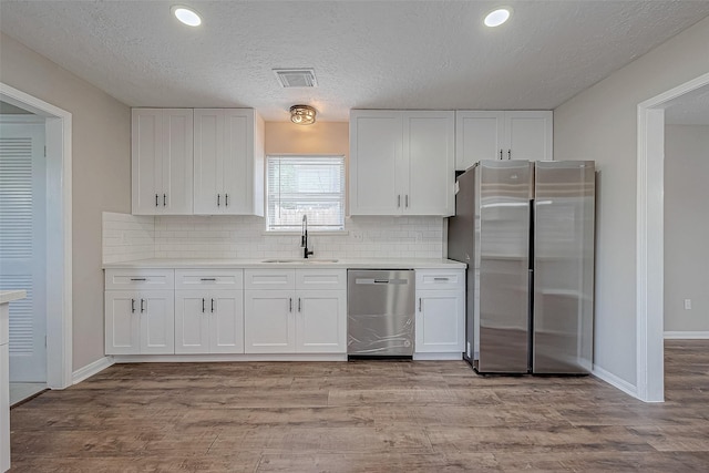 kitchen featuring white cabinets, backsplash, stainless steel appliances, and sink