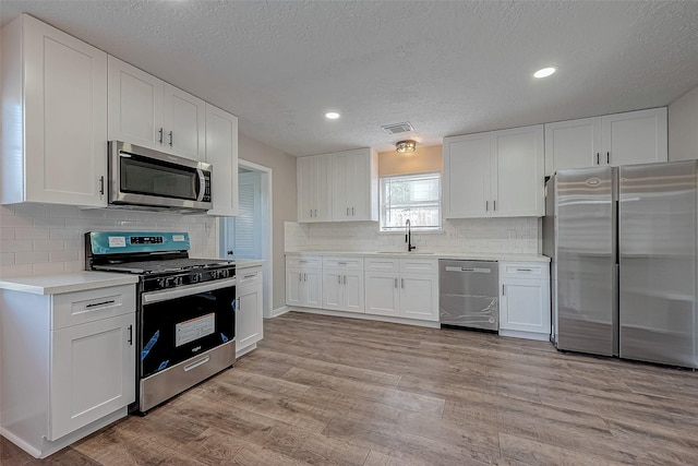 kitchen with white cabinets, appliances with stainless steel finishes, a textured ceiling, and sink