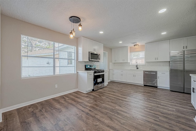 kitchen with pendant lighting, decorative backsplash, white cabinetry, and stainless steel appliances