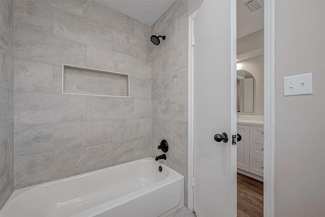 bathroom featuring hardwood / wood-style flooring, vanity, and tiled shower / bath