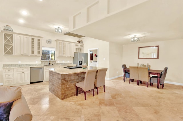 kitchen featuring a center island, a kitchen breakfast bar, sink, appliances with stainless steel finishes, and light stone counters