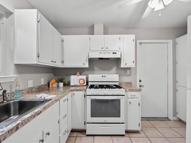 kitchen featuring sink, ceiling fan, white gas range, light tile patterned flooring, and white cabinetry