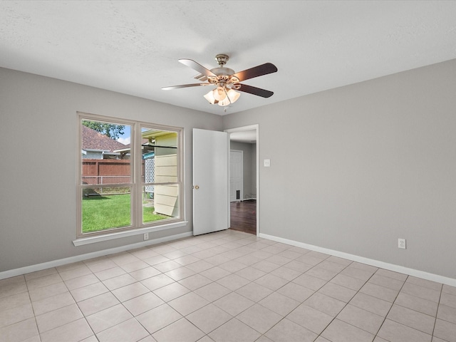 spare room with ceiling fan and light tile patterned floors