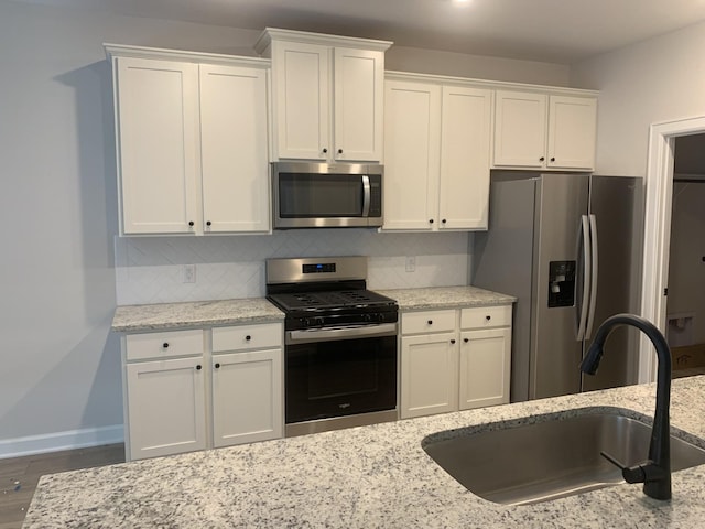 kitchen featuring tasteful backsplash, white cabinetry, sink, and appliances with stainless steel finishes