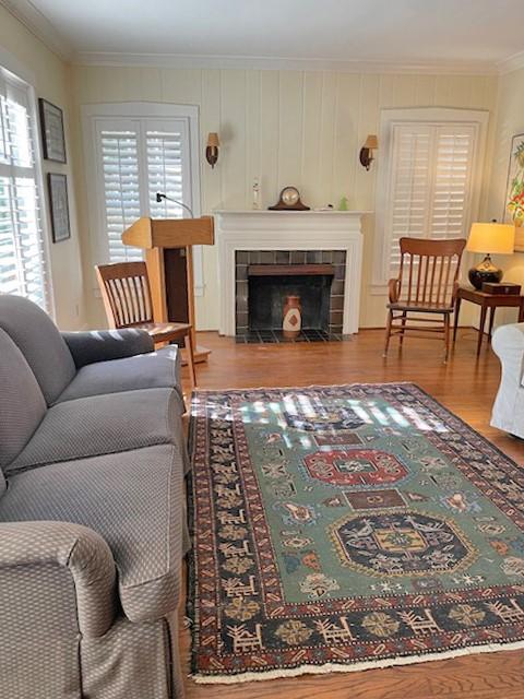 living room featuring a fireplace, wood-type flooring, and ornamental molding