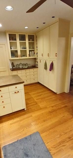 kitchen with white cabinets, ceiling fan, backsplash, and light hardwood / wood-style flooring