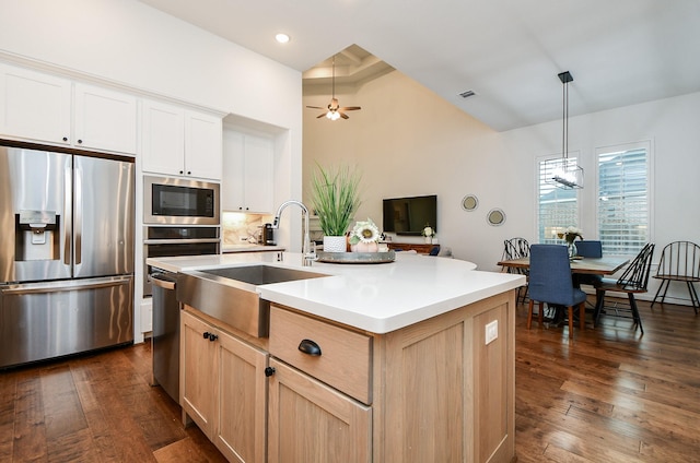 kitchen featuring ceiling fan, light brown cabinets, stainless steel appliances, pendant lighting, and a kitchen island with sink