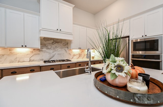 kitchen with decorative backsplash, stainless steel appliances, white cabinetry, and sink