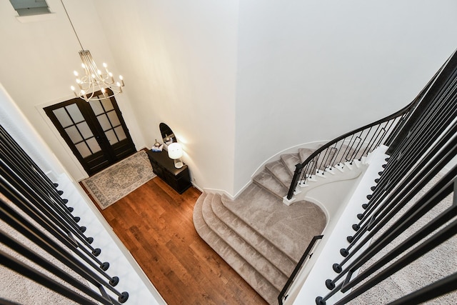 stairway featuring hardwood / wood-style flooring and an inviting chandelier