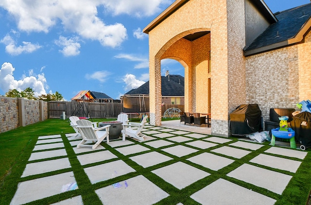 view of patio / terrace with area for grilling, a trampoline, and a fire pit