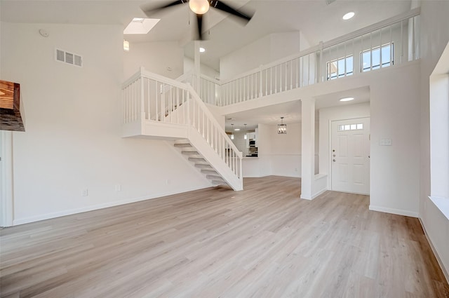 foyer featuring ceiling fan, light hardwood / wood-style floors, and a high ceiling