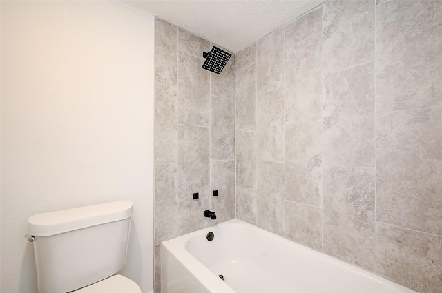 bathroom featuring a textured ceiling, toilet, and tiled shower / bath