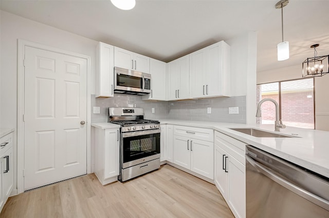 kitchen with sink, white cabinetry, stainless steel appliances, and hanging light fixtures