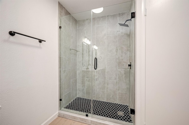 bathroom with wood-type flooring and a shower with shower door