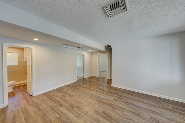 unfurnished room with a textured ceiling and light hardwood / wood-style flooring