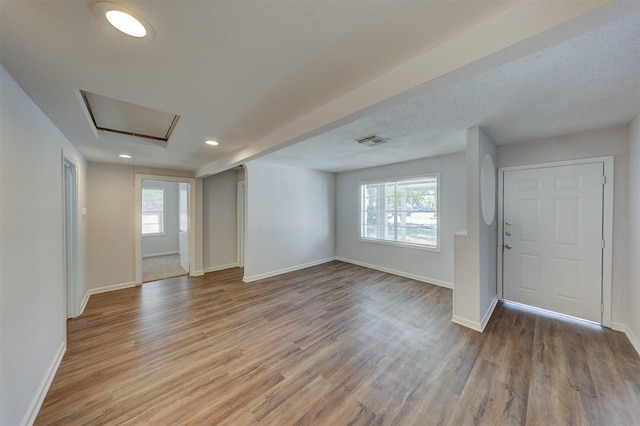 foyer entrance with a wealth of natural light, light hardwood / wood-style floors, and a textured ceiling