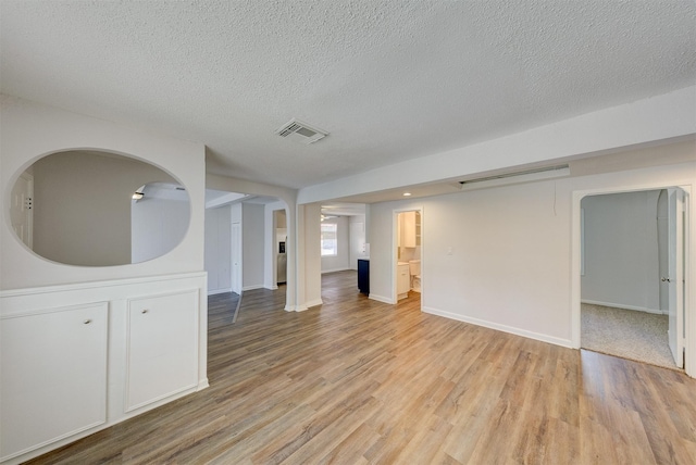 empty room featuring light wood-type flooring and a textured ceiling