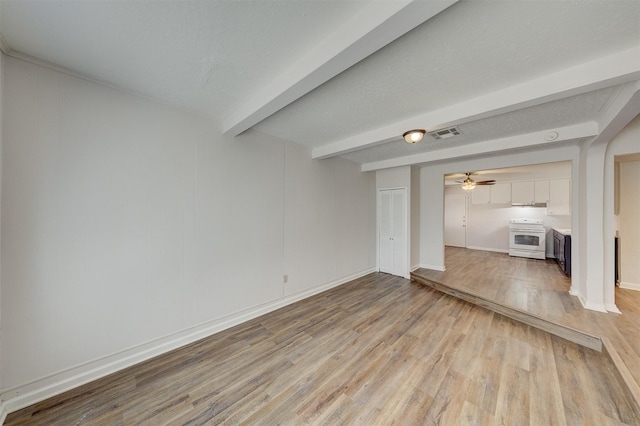 unfurnished living room featuring ceiling fan, light hardwood / wood-style flooring, beamed ceiling, and a textured ceiling