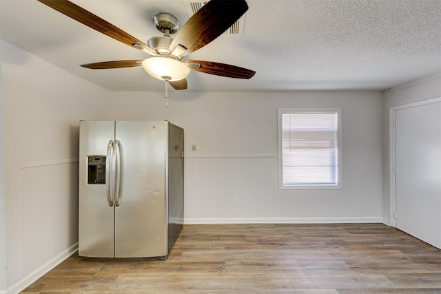 interior space featuring ceiling fan, light wood-type flooring, and a textured ceiling