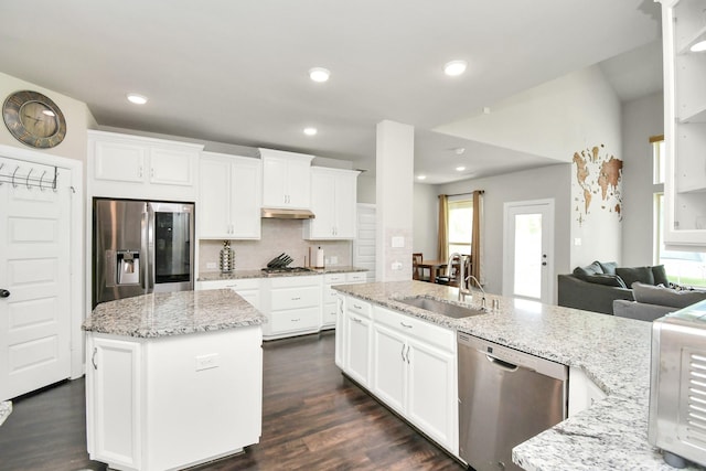 kitchen with a kitchen island with sink, white cabinets, sink, appliances with stainless steel finishes, and light stone counters