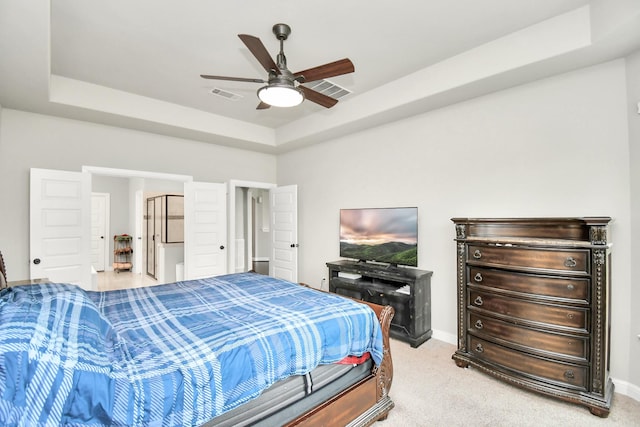 bedroom with a raised ceiling, ceiling fan, and light carpet