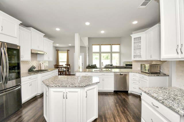 kitchen with white cabinets, sink, decorative backsplash, appliances with stainless steel finishes, and kitchen peninsula