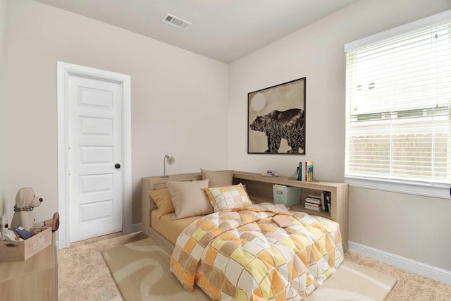 bedroom with light colored carpet and multiple windows