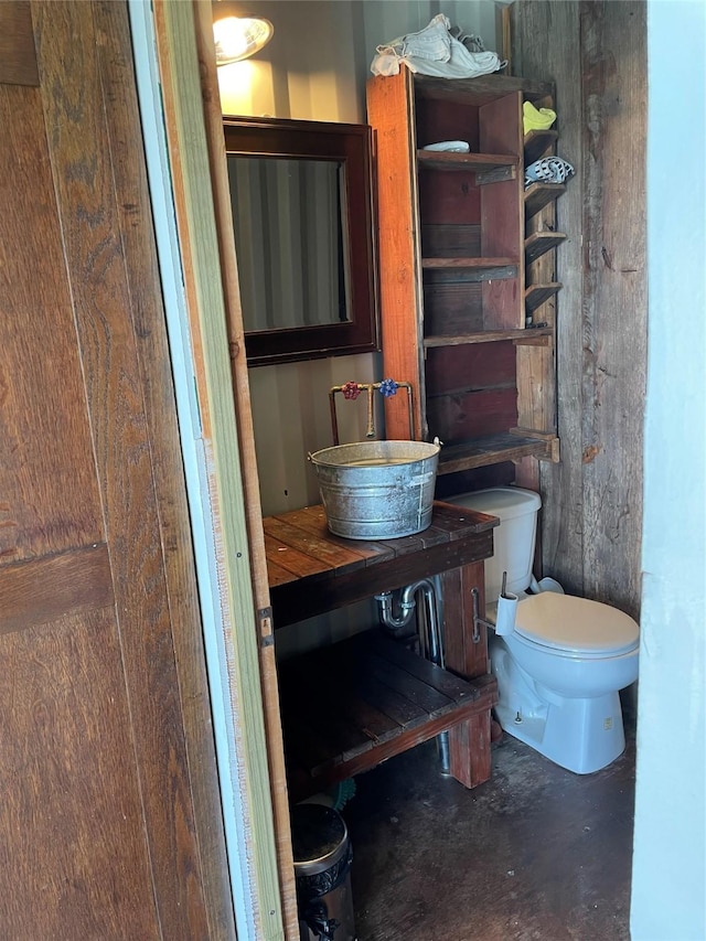 bathroom featuring toilet, sink, and concrete floors