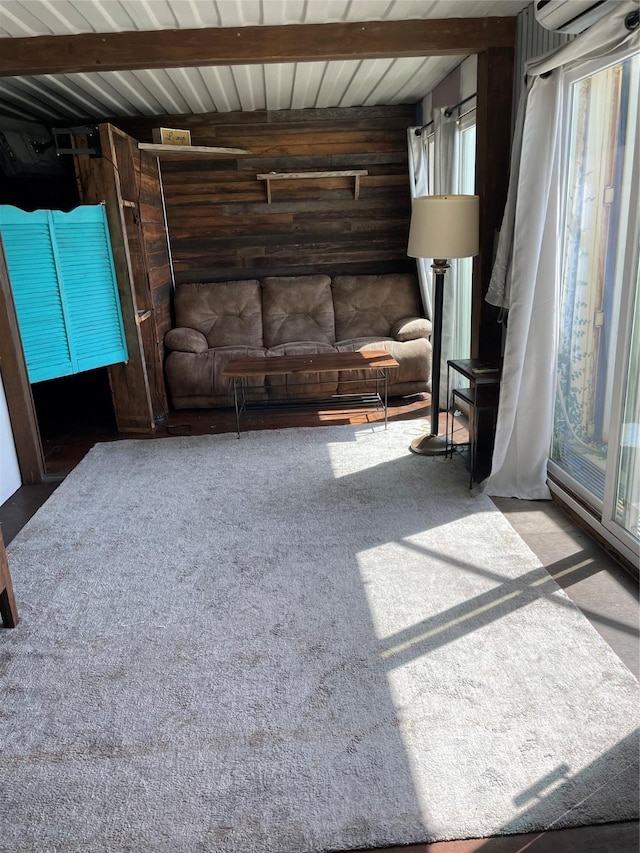 carpeted living room featuring beamed ceiling and wooden walls