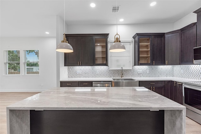 kitchen featuring appliances with stainless steel finishes, backsplash, hanging light fixtures, and sink