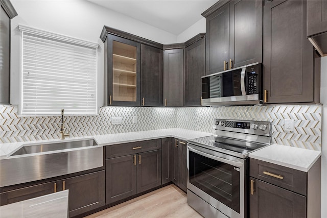 kitchen with decorative backsplash, dark brown cabinets, stainless steel appliances, sink, and light hardwood / wood-style floors