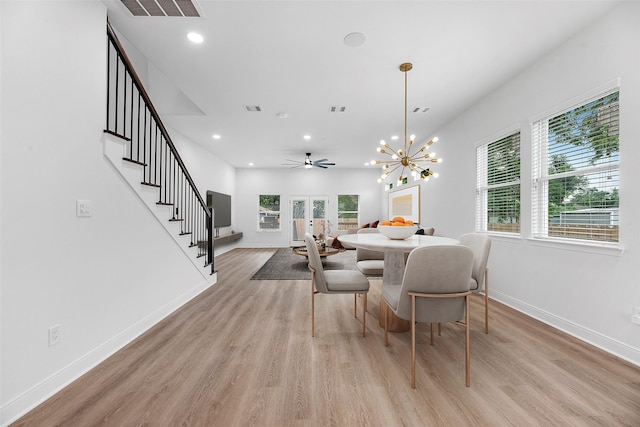 dining area with french doors, ceiling fan with notable chandelier, and light hardwood / wood-style flooring