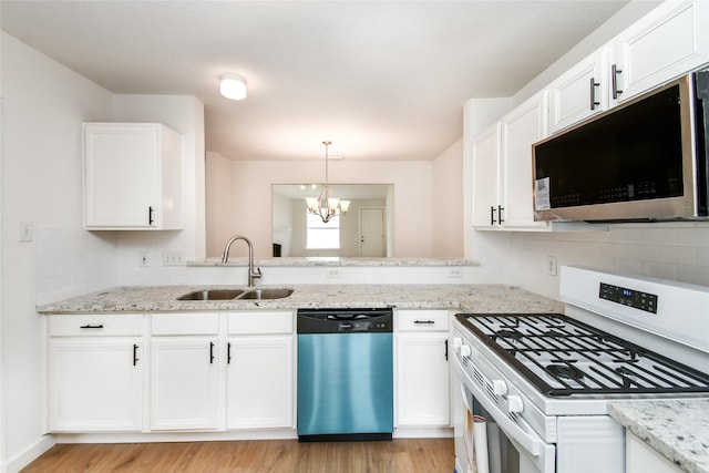 kitchen with sink, white cabinets, stainless steel appliances, and an inviting chandelier