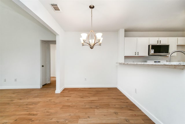 kitchen with a chandelier, pendant lighting, light hardwood / wood-style flooring, and white cabinetry