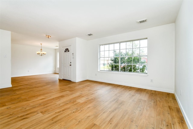 spare room featuring light hardwood / wood-style flooring and a chandelier