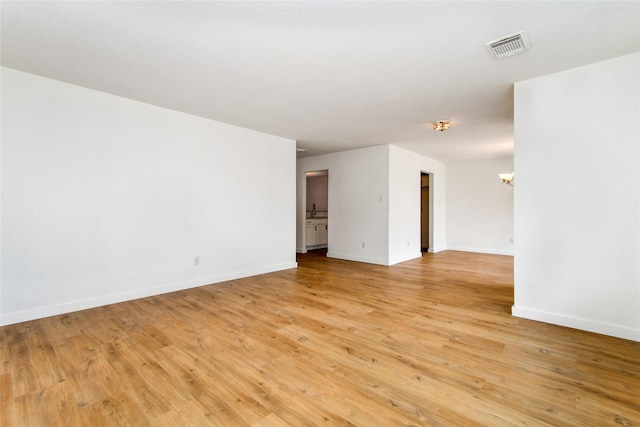 empty room with light hardwood / wood-style flooring and a notable chandelier