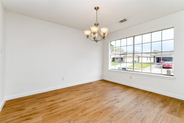 spare room with wood-type flooring and a chandelier