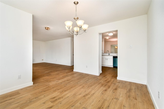 unfurnished room with light wood-type flooring, sink, and a chandelier