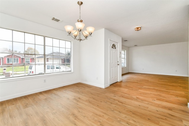 empty room with light hardwood / wood-style flooring and a chandelier