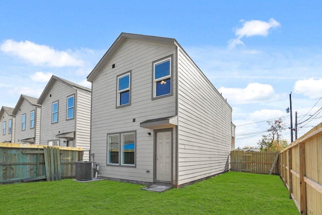 rear view of property featuring a lawn and cooling unit