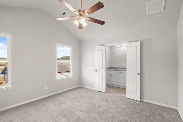 unfurnished bedroom with multiple windows, ceiling fan, light colored carpet, and vaulted ceiling