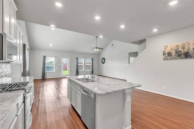 kitchen featuring appliances with stainless steel finishes, light wood-type flooring, sink, white cabinetry, and an island with sink