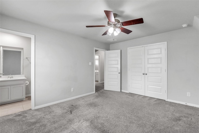 unfurnished bedroom featuring ceiling fan, a closet, ensuite bathroom, and light carpet