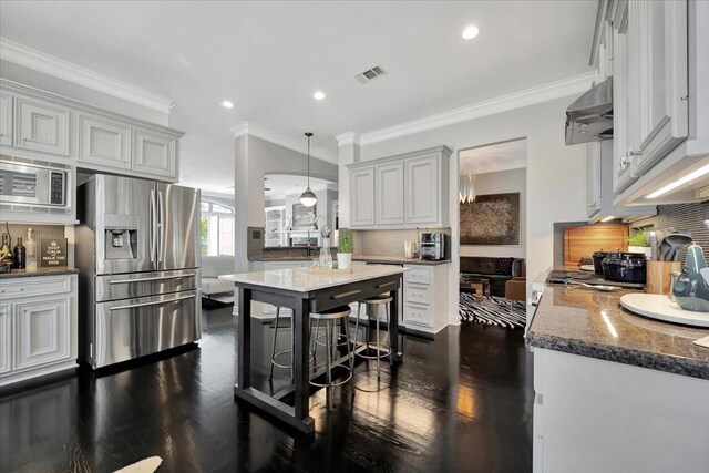 kitchen with backsplash, ornamental molding, stainless steel appliances, and dark stone counters