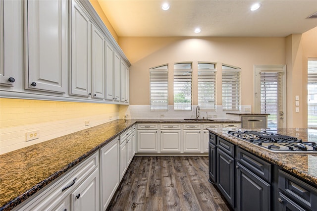 kitchen featuring sink, white cabinetry, stainless steel gas stovetop, and dark stone countertops